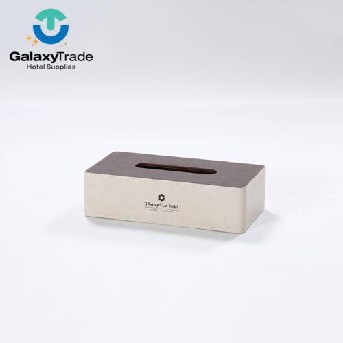 A Shangri-La branded luxury hotel rectangular tissue box cover in beige faux leather with a dark wood-grain top.