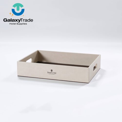 A Shangri-La branded luxury hotel service tray in beige faux leather featuring integrated oval side handles and a dark brown interior base.