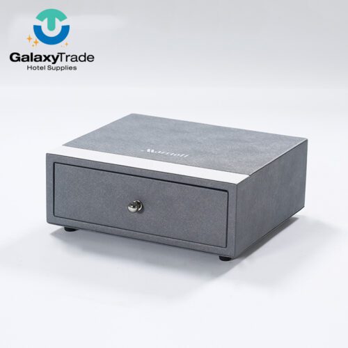 A Marriott Shanghai Luwan branded luxury hotel drawer box in grey faux leather with a white trim, metallic knob, and rectangular profile.