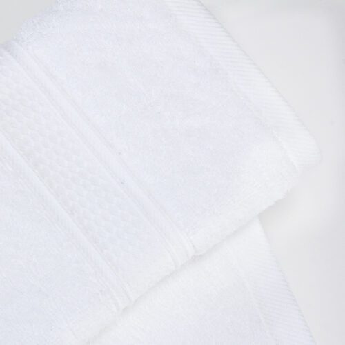Close-up detail of a premium white plush cotton towel featuring an elegant diamond-patterned textured dobby border.