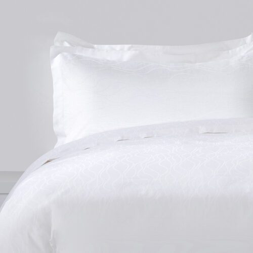 Luxury white hotel bedding set featuring a subtle tonal wave jacquard pattern on the duvet and pillowcases.