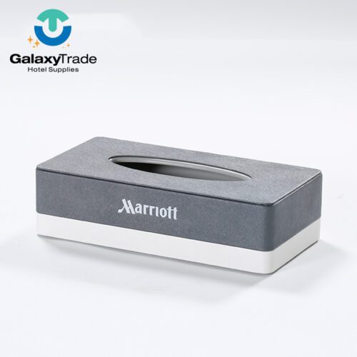A Marriott Shanghai Luwan branded luxury hotel rectangular tissue box cover in grey faux leather with a white base and oval top opening.