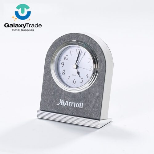 A Marriott Shanghai Luwan branded luxury hotel desk clock in grey faux leather with a chrome-rimmed quartz face and silver base.