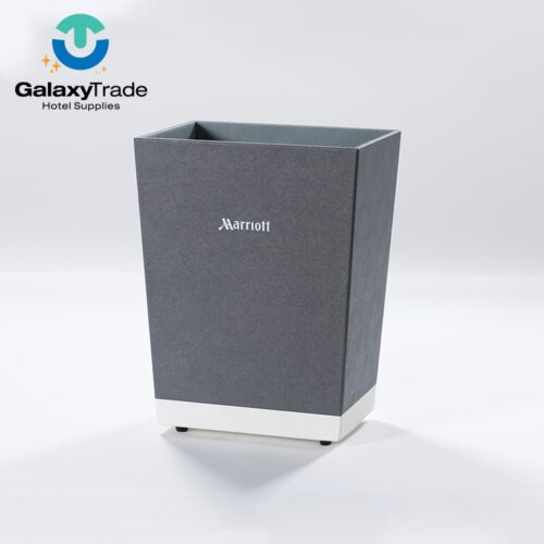 A Marriott Shanghai Luwan branded luxury hotel waste basket in grey faux leather with a white base and non-slip feet.
