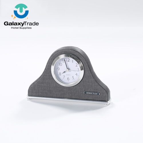 A Crowne Plaza branded luxury hotel desk clock in grey faux leather with a polished chrome base and analog face.