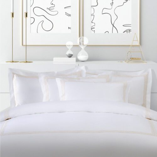 Luxury white hotel bedding set featuring a stack of pillowcases and a duvet cover with gold wheat motif embroidery.