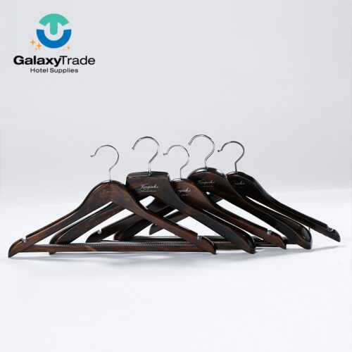 A professional shot of multiple Dark Walnut Solid Wood Hotel Hangers custom branded for Kempinski.