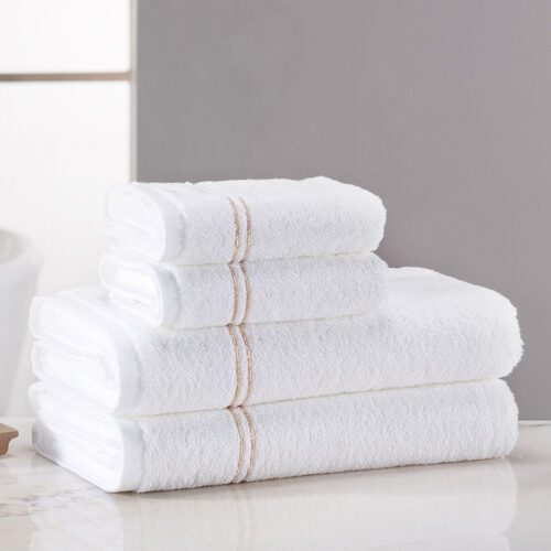 A stack of folded premium white plush cotton towels featuring wide, elegant double gold sateen borders.