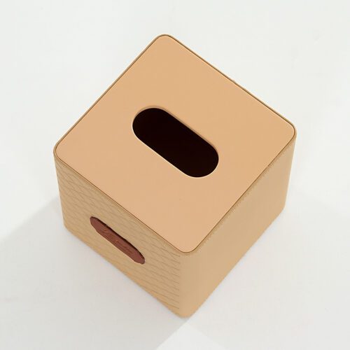 A top-down perspective shot of a Kempinski branded square beige faux leather tissue box cover with textured diamond-embossed sides.