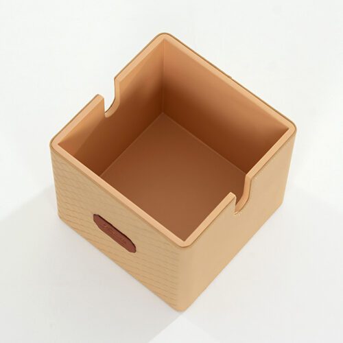 A professional product shot of a Kempinski branded beige faux leather square tissue box cover with a diamond-patterned exterior.