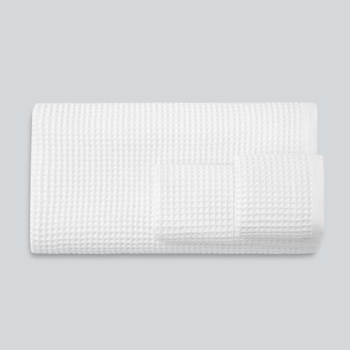 A set of folded white plush cotton towels featuring a distinct and uniform waffle weave texture.