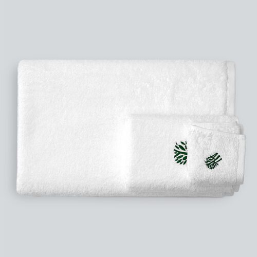 A set of folded white plush cotton towels featuring a delicate green leaf embroidery and a textured dobby border.