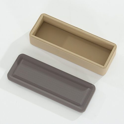 A top-down shot of a Marriott branded beige faux leather remote control storage box with its grey textured lid placed alongside it.