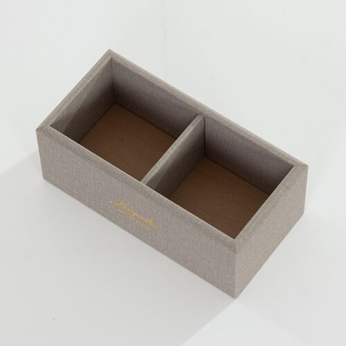 A professional collection shot of three Kempinski branded grey textured faux leather desk accessories, including a notepad holder and a remote caddy.