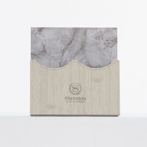 A Sheraton branded luxury hotel notepad holder with a wave-cut grey linen exterior and grey marble-patterned leather interior.