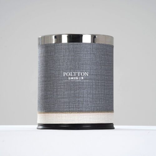 A professional product shot of a POLTTON branded round waste bin with a grey linen-textured faux leather finish and chrome rim.