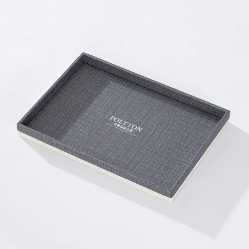 A professional product shot of a square POLTTON branded grey linen-textured faux leather hospitality service tray.