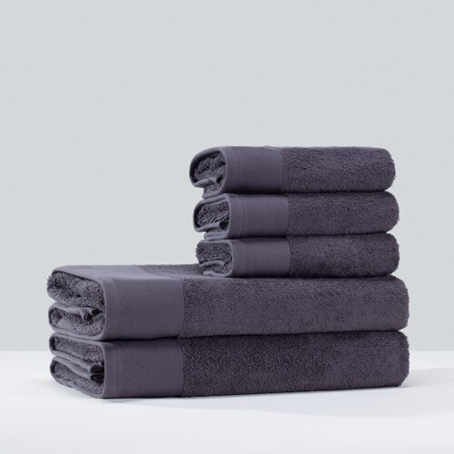 A stack of neatly folded charcoal grey plush cotton towels, including bath towels and hand towels, against a clean background.