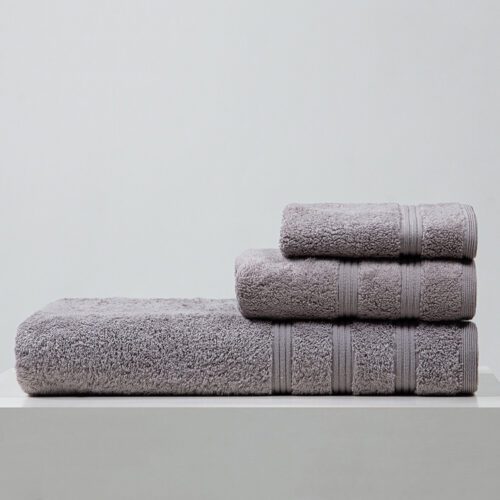 A stack of three neatly folded light grey plush cotton towels, showing the textured ribbed border detail against a clean white background.