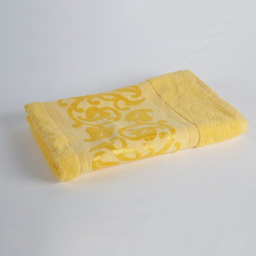 A neatly folded vibrant yellow plush cotton towel featuring a detailed raised floral jacquard pattern.