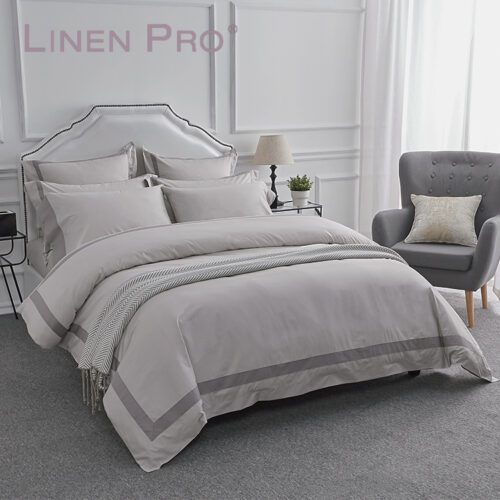 A modern luxury bed featuring a dove grey duvet cover with a charcoal grey frame border and matching pillowcases.