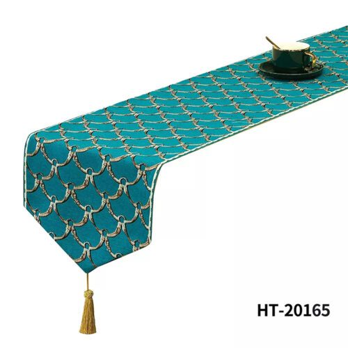 A teal bed runner with a golden fish scale jacquard pattern and a decorative gold tassel.