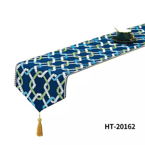 A navy blue nautical bed runner with an interlocking rope pattern in white, green, and blue, featuring a gold tassel.