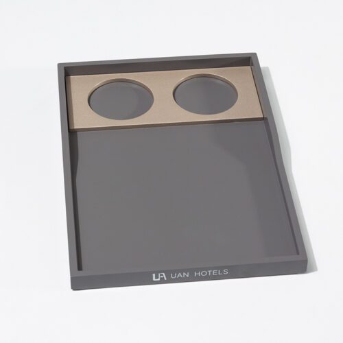A professional product view of a UAN HOTELS branded matte grey lacquered amenity tray with a dual cup holder insert.