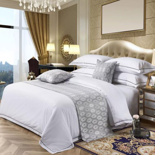 A modern hotel bed with white linens featuring a vibrant teal bedspread with black and white zigzag patterns and matching pillows.