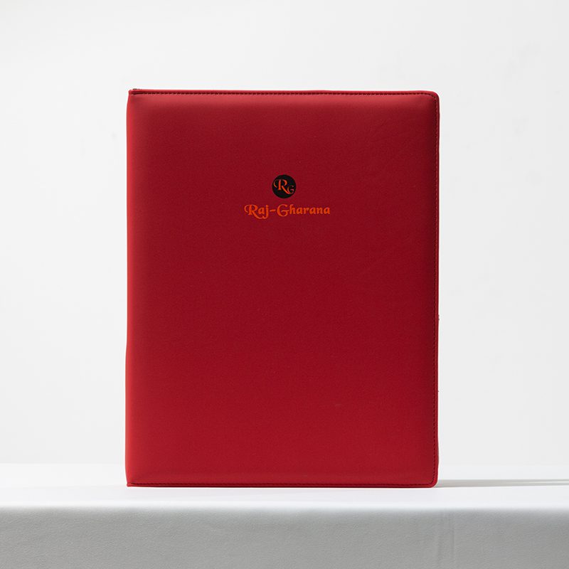 A professional product shot of a Raj-Gharana branded red matte leather folder for luxury hotel guest directories.