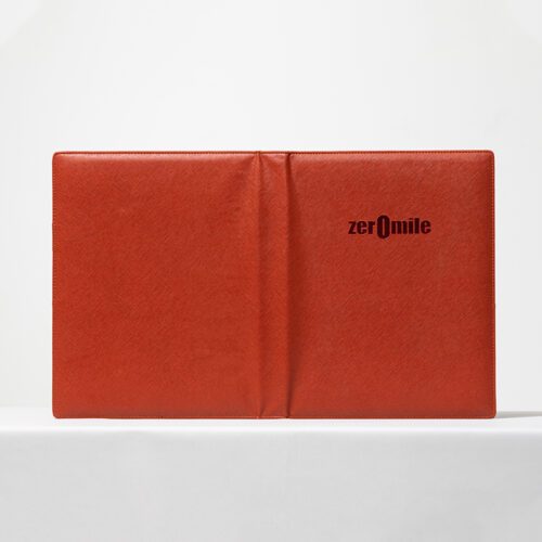 A professional product shot of a Zero Mile branded orange lychee grain leather folder for luxury hotel guest directories.