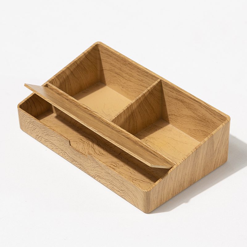 An interior view of a Banyan Tree branded natural wood divided storage box for hotel guest room amenities.