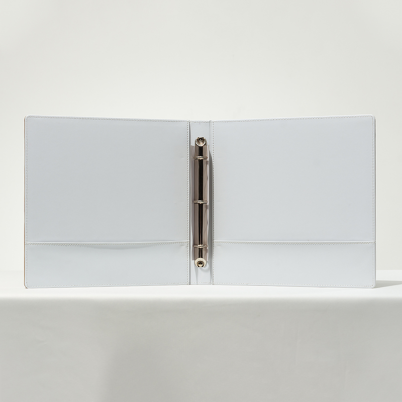 An open interior view of a Banyan Tree branded white leather 3-ring guest directory binder with metal rings and pockets.