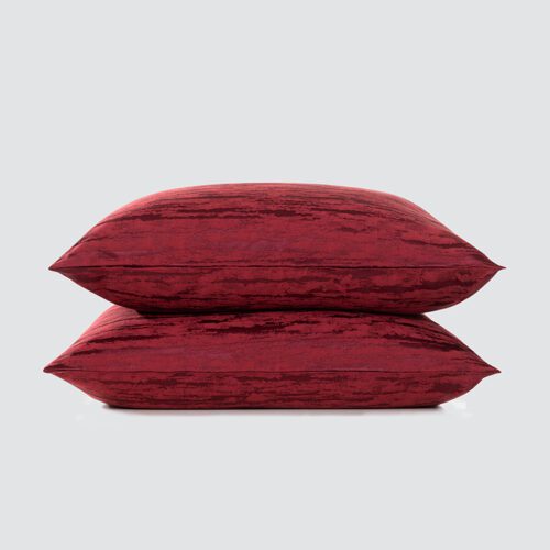 A stack of two luxury burgundy throw pillows with a weathered tonal abstract pattern and a soft satin sheen.