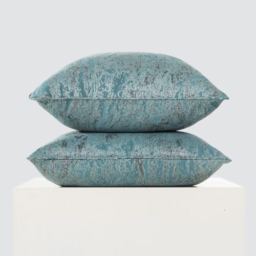 A high-resolution product shot of a stack of two Ocean Teal Abstract Metallic Pillows featuring a distressed silver foil pattern and a lustrous seafoam green-blue finish.