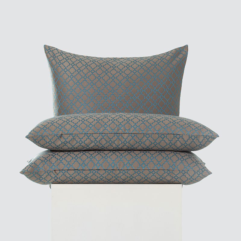 A high-resolution product shot of a three-piece Warm Taupe and Teal Quatrefoil Embroidered Pillow set featuring a teal geometric pattern and a matte taupe background.