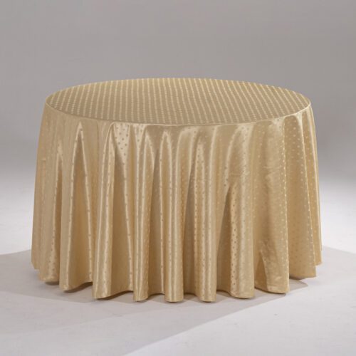 A large champagne gold round polyester tablecloth with an intricate snowflake jacquard pattern draped over a banquet table.