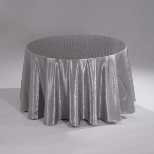 A large silver round polyester tablecloth with an intricate snowflake jacquard pattern draped over a banquet table.