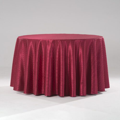A large vibrant red round polyester tablecloth with an intricate snowflake jacquard pattern draped over a banquet table.