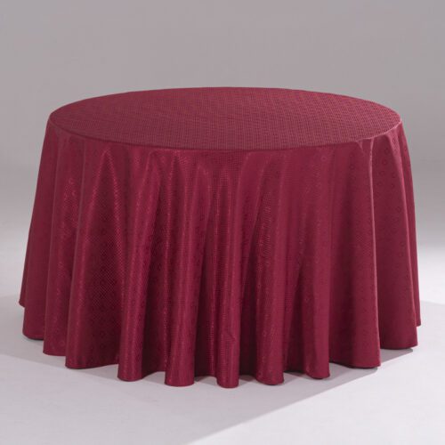 A large red round polyester tablecloth with an intricate cross-grid jacquard pattern draped over a banquet table.