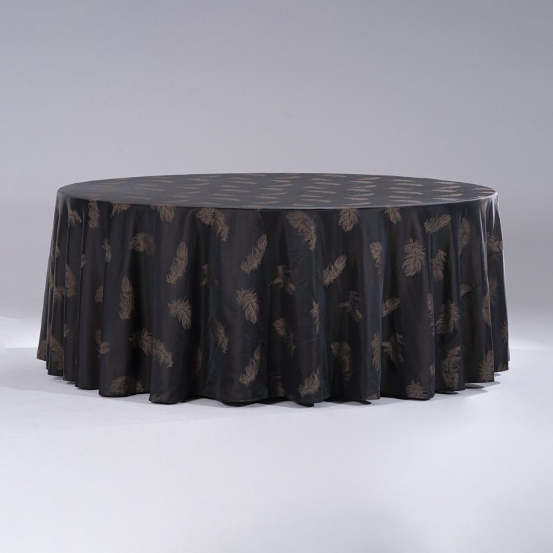 A large black round polyester tablecloth with elegant metallic gold feather jacquard patterns draped over a banquet table.