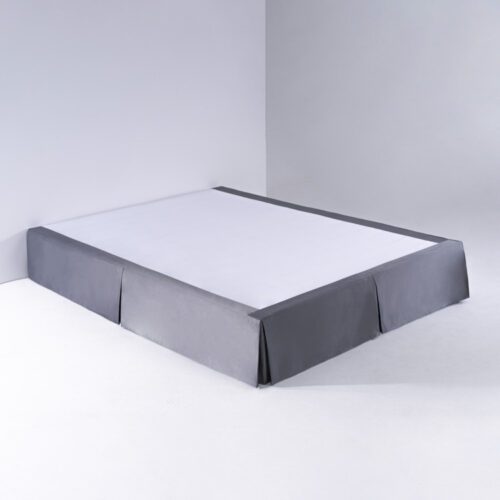 A modern slate grey pleated bed skirt installed on a hotel bed frame with a clean white platform.