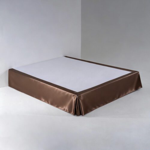 A professional chocolate brown satin bed skirt with tailored box pleats and a high-gloss finish on a white hotel bed base.