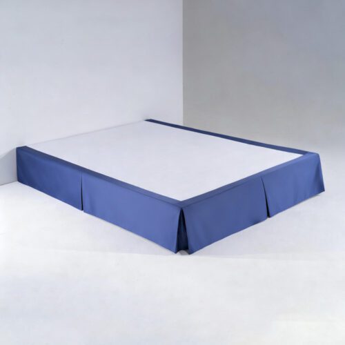 A tailored royal blue hotel bed skirt with clean box pleats fitted on a white bed base.