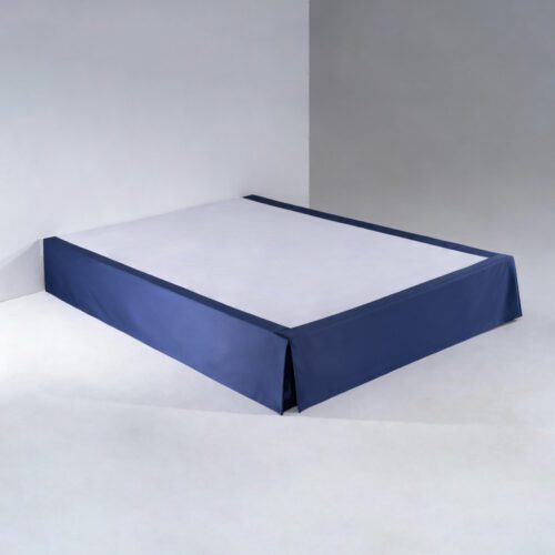 A minimalist midnight blue hotel bed skirt with tailored box pleats installed on a professional bed base.