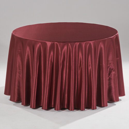 A large burgundy round polyester tablecloth with a subtle raindrop jacquard pattern draped over a banquet table in a professional setting.