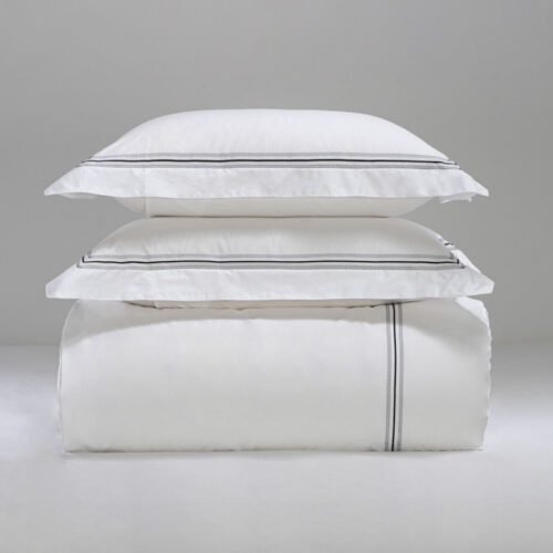 A stack of luxury white hotel pillows and a duvet featuring black embroidered linear detailing.