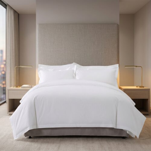 A fully dressed hotel bed featuring white linens with teal linear embroidery and decorative starfish pillows.