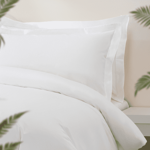 Close-up of luxury white hotel bedding featuring a duvet and stacked Oxford pillowcases with wide-stitched flanges.