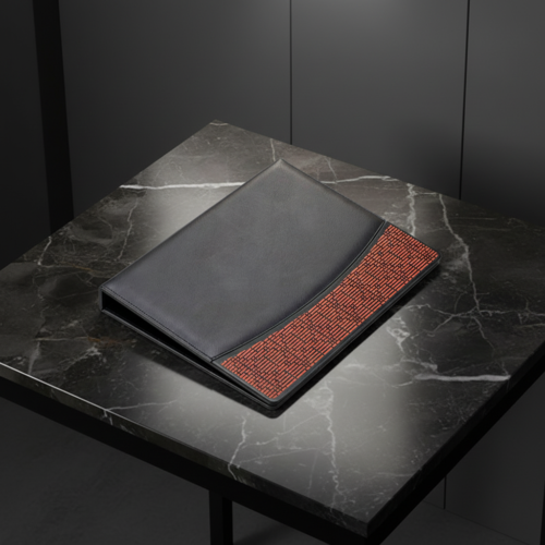 A premium black leather hotel guest directory folder featuring a rust-orange woven accent strip on a dark marble countertop.
